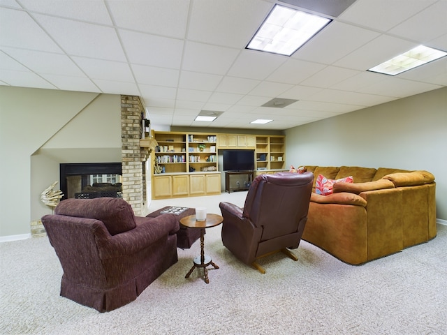 living room with a drop ceiling, brick wall, built in shelves, and light carpet