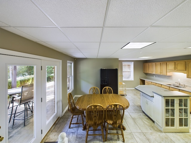 tiled dining area with sink and a paneled ceiling