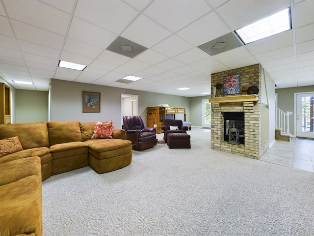 living room featuring a fireplace, a paneled ceiling, brick wall, and light carpet