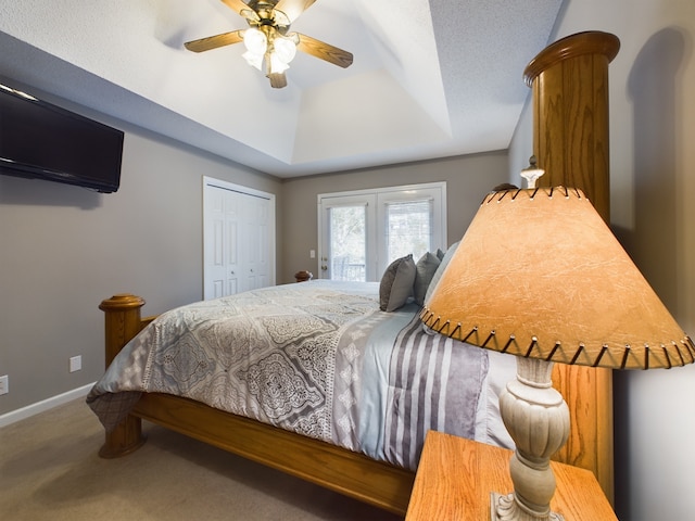 bedroom with ceiling fan, a tray ceiling, a closet, french doors, and carpet floors