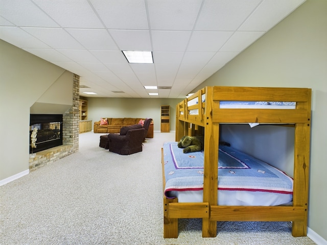 carpeted bedroom with brick wall, a paneled ceiling, and a brick fireplace