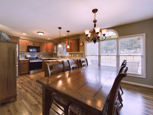 dining area featuring hardwood / wood-style flooring, an inviting chandelier, sink, and a textured ceiling