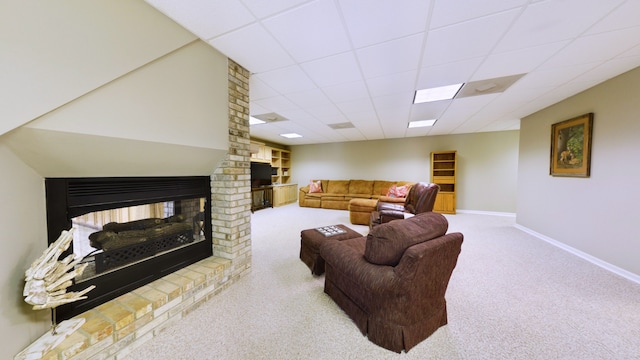 carpeted living room with brick wall, a paneled ceiling, and a brick fireplace