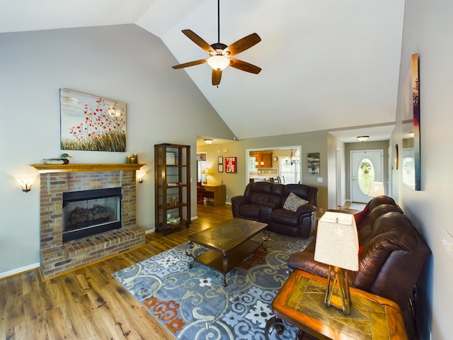 living room featuring ceiling fan, high vaulted ceiling, wood-type flooring, and a brick fireplace