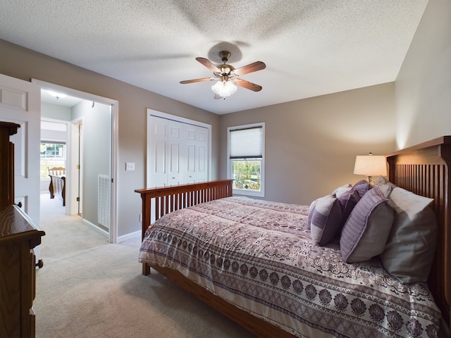 carpeted bedroom with ceiling fan, a textured ceiling, and a closet