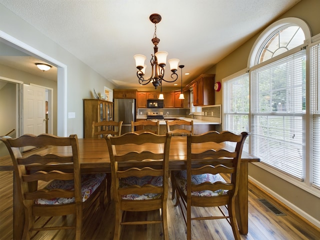 dining room with hardwood / wood-style flooring, sink, and a notable chandelier