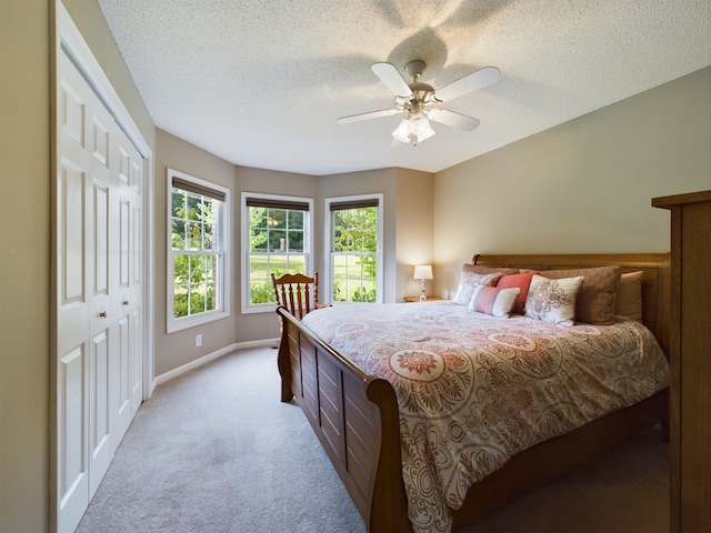 carpeted bedroom featuring ceiling fan, a closet, and a textured ceiling