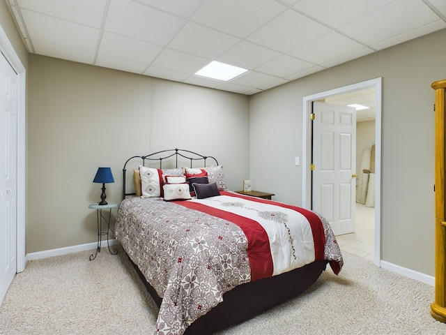 carpeted bedroom with a closet and a paneled ceiling