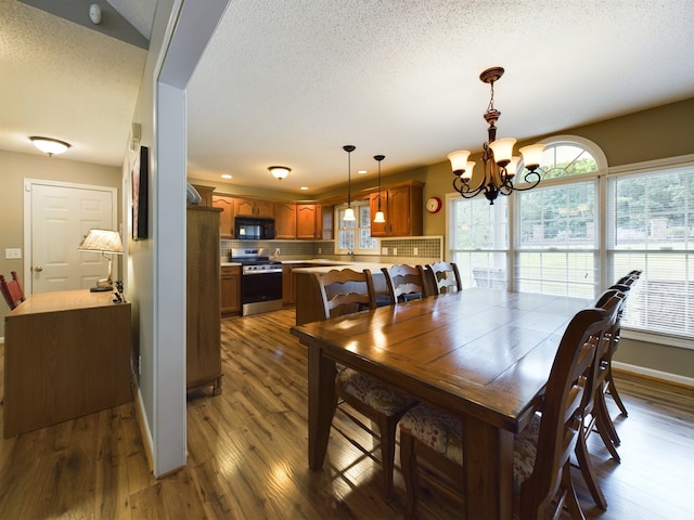 dining space with a notable chandelier, a textured ceiling, and dark hardwood / wood-style flooring