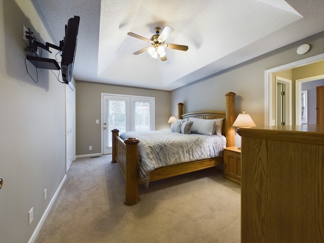 carpeted bedroom with a tray ceiling, ceiling fan, a textured ceiling, and french doors