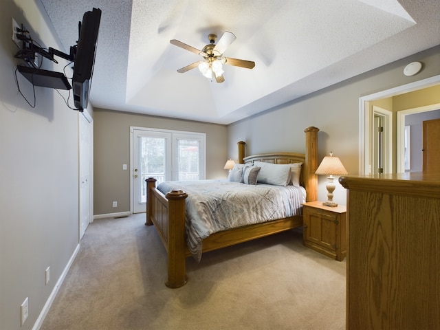 carpeted bedroom with a textured ceiling, a tray ceiling, ceiling fan, and access to exterior