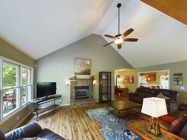 living room with ceiling fan, vaulted ceiling, hardwood / wood-style floors, and a brick fireplace