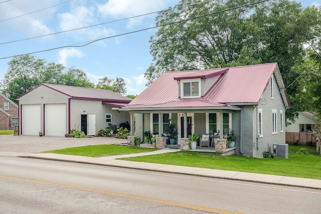 view of front of home with central AC unit, a porch, a front yard, a garage, and an outbuilding