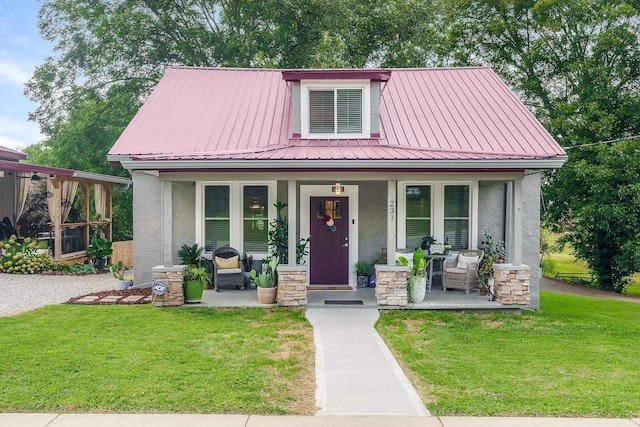 view of front of house with covered porch, metal roof, a front yard, and stucco siding