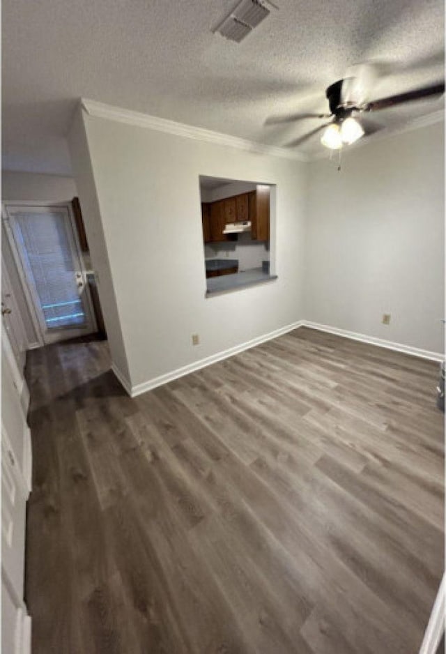 unfurnished room with visible vents, ornamental molding, a ceiling fan, wood finished floors, and baseboards