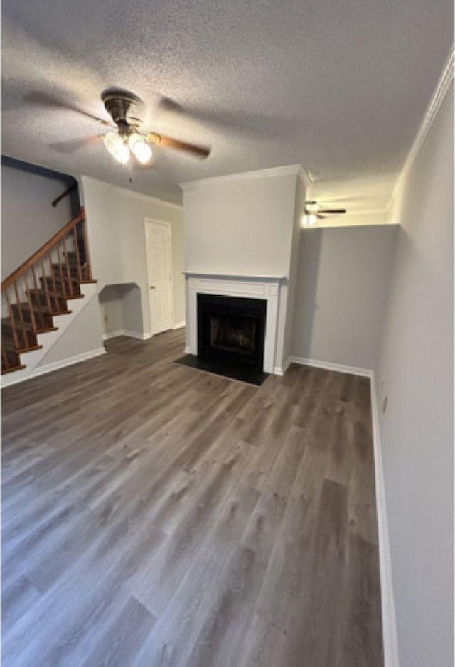 unfurnished living room with dark wood-style flooring, crown molding, a fireplace with flush hearth, a ceiling fan, and a textured ceiling