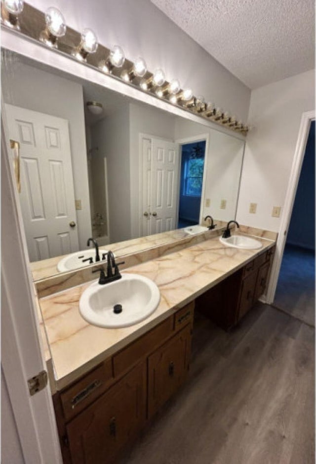 bathroom featuring double vanity, a textured ceiling, and a sink