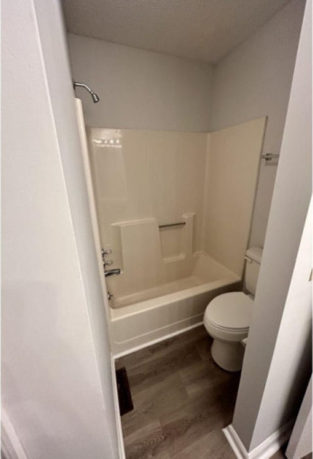 bathroom featuring tub / shower combination, wood finished floors, and toilet