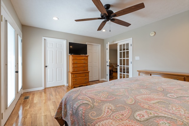 bedroom with ceiling fan, light wood-type flooring, french doors, and multiple windows