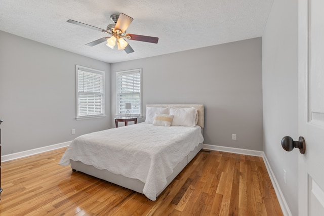 bedroom featuring ceiling fan, light hardwood / wood-style flooring, and a textured ceiling