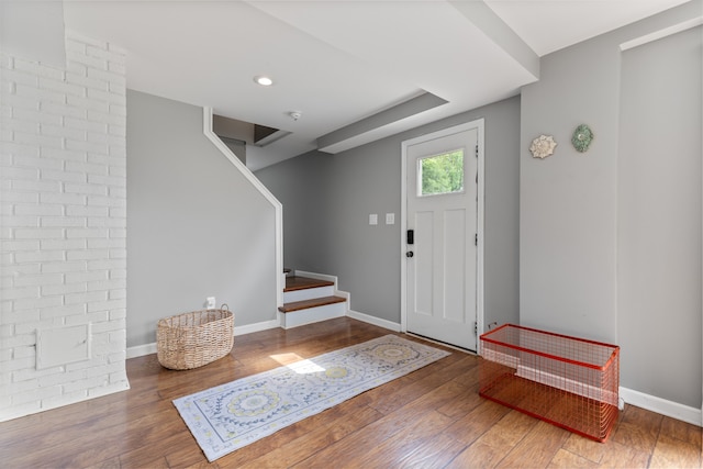 entryway with brick wall and hardwood / wood-style flooring