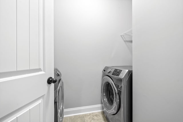 clothes washing area featuring laundry area, washing machine and dryer, and baseboards