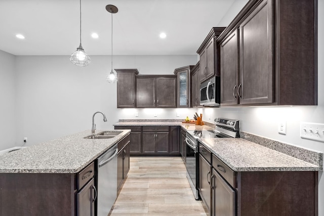 kitchen with stainless steel appliances, dark brown cabinets, a sink, and light wood-style flooring