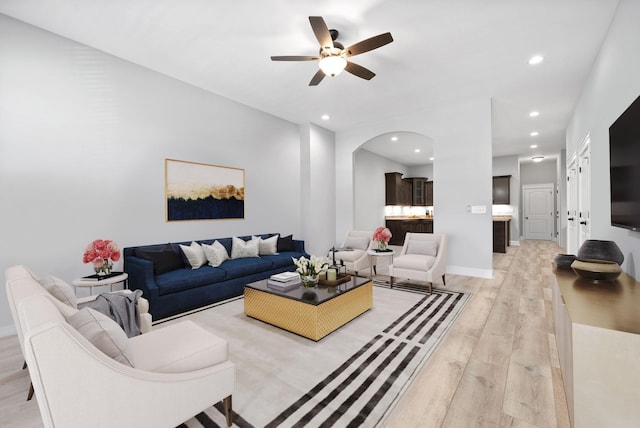 living room with arched walkways, recessed lighting, ceiling fan, light wood-type flooring, and baseboards