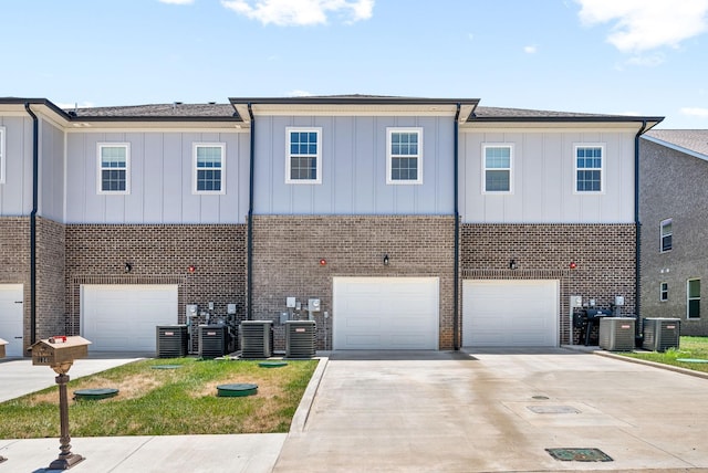 view of front of home featuring driveway, brick siding, board and batten siding, and cooling unit