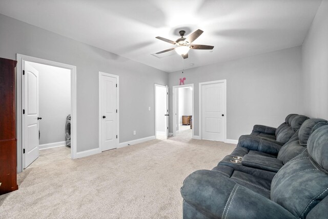 living room with ceiling fan, washer / dryer, and light colored carpet