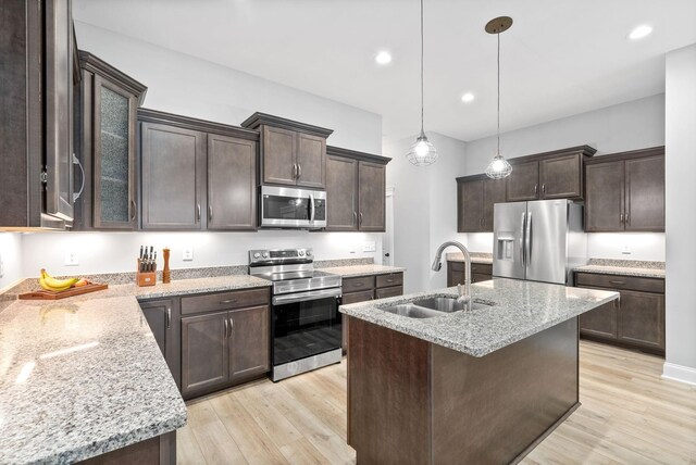 kitchen featuring sink, light wood-type flooring, dark brown cabinets, light stone counters, and stainless steel appliances