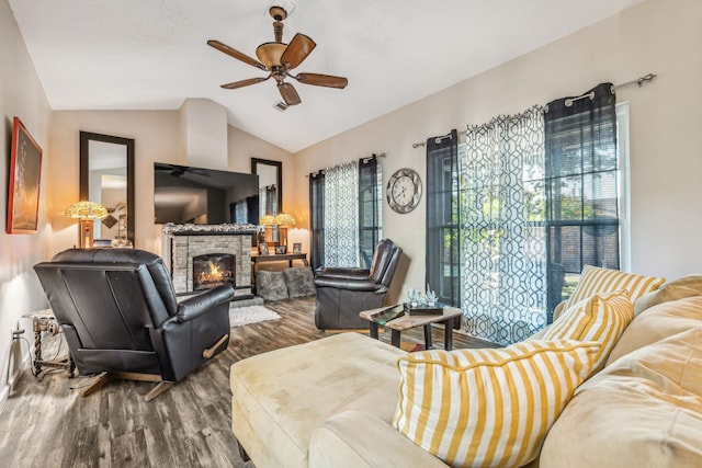 living room featuring ceiling fan, a stone fireplace, wood-type flooring, and lofted ceiling