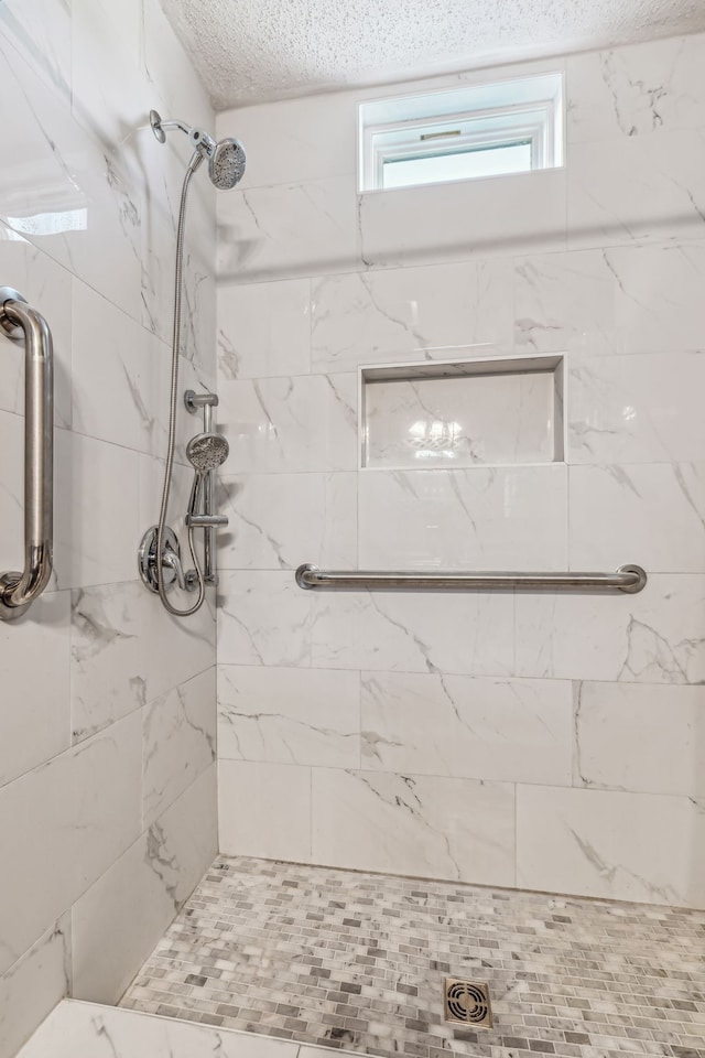 bathroom featuring a textured ceiling and a tile shower