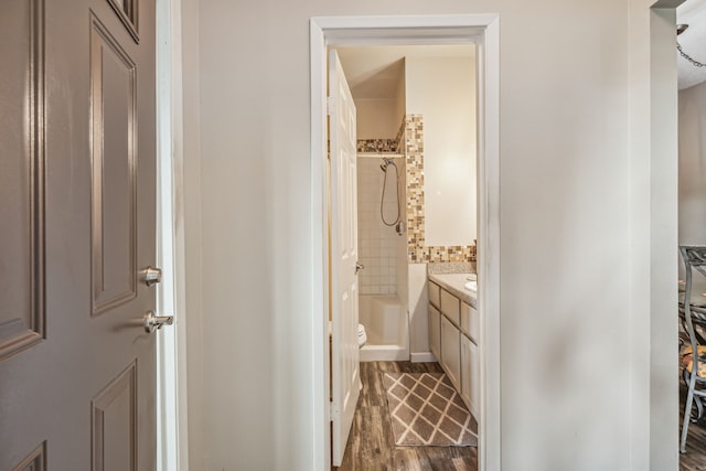 full bathroom with toilet, vanity, tiled shower / bath, and wood-type flooring