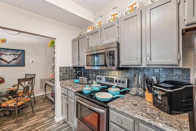 kitchen featuring light stone countertops, appliances with stainless steel finishes, backsplash, and dark hardwood / wood-style flooring