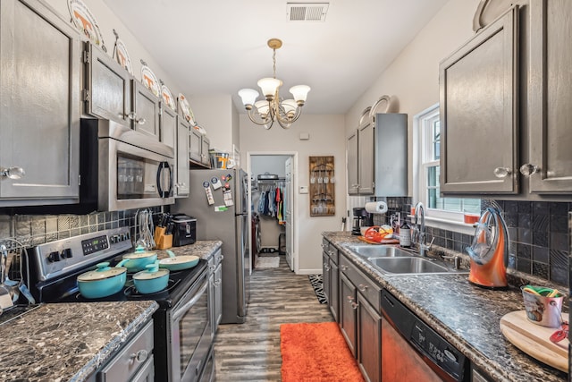 kitchen with sink, an inviting chandelier, appliances with stainless steel finishes, wood-type flooring, and decorative backsplash