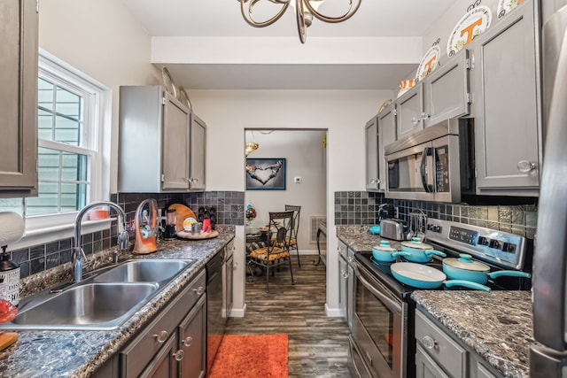 kitchen with sink, dark hardwood / wood-style flooring, appliances with stainless steel finishes, tasteful backsplash, and gray cabinetry