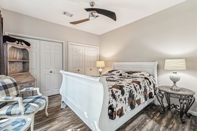 bedroom featuring ceiling fan, dark hardwood / wood-style floors, and multiple closets