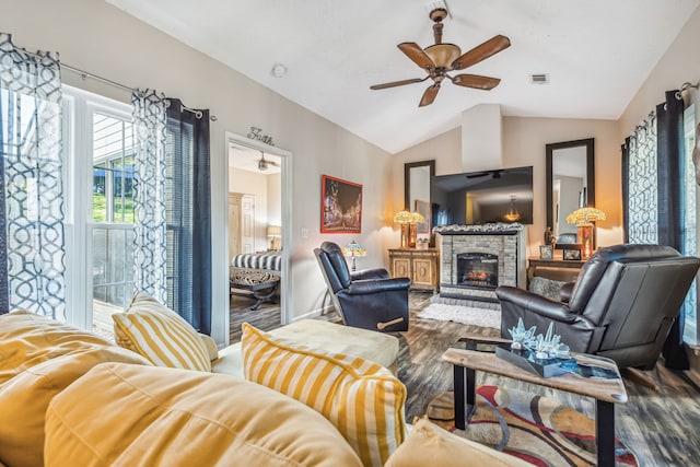 living room with dark hardwood / wood-style flooring, ceiling fan, lofted ceiling, and a stone fireplace