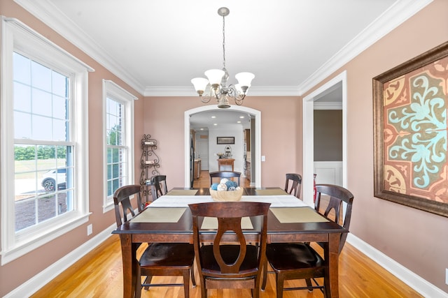 dining area featuring ornamental molding, a notable chandelier, and light hardwood / wood-style flooring