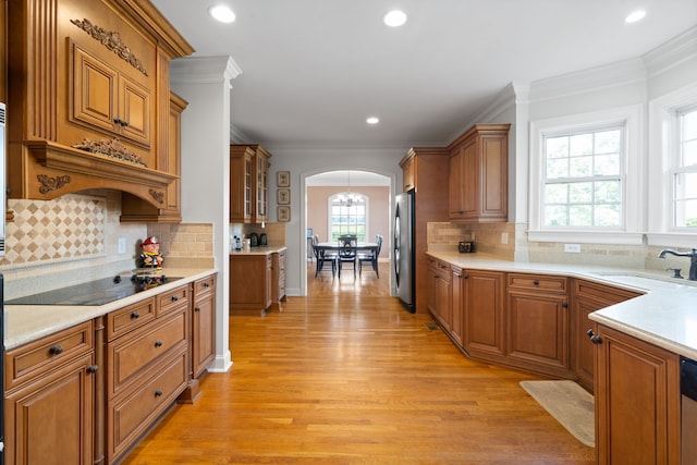 kitchen featuring appliances with stainless steel finishes, plenty of natural light, ornamental molding, and light hardwood / wood-style floors