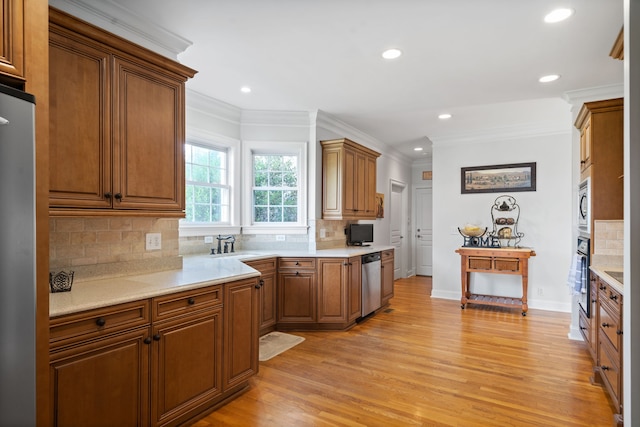 kitchen featuring light wood-type flooring, sink, stainless steel appliances, backsplash, and ornamental molding