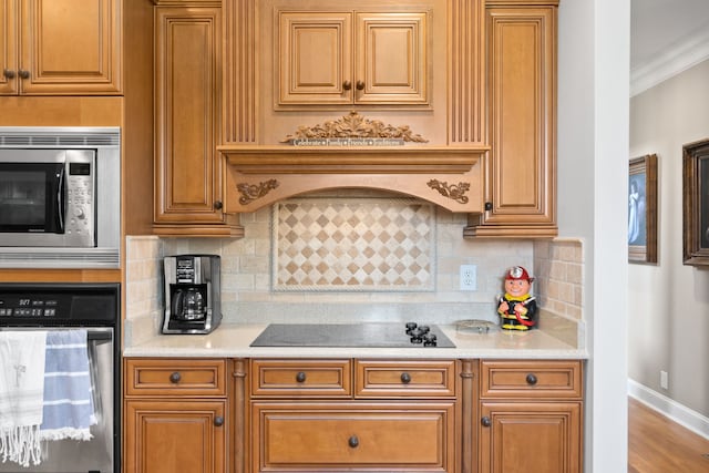 kitchen featuring crown molding, backsplash, black appliances, premium range hood, and hardwood / wood-style flooring