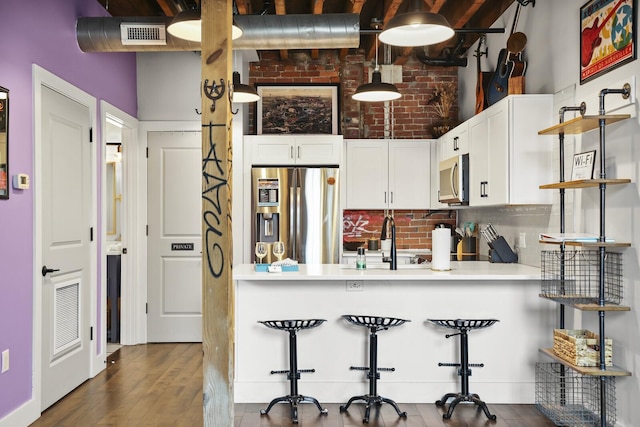 610 21st Ave N Unit 101, Nashville, TN 37203 - kitchen with appliances with stainless steel finishes, open shelves, a peninsula, white cabinets, and brick wall