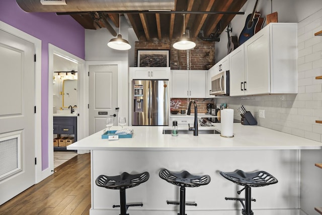 610 21st Ave N Unit 101, Nashville, TN 37203 - kitchen featuring stainless steel appliances, a peninsula, white cabinets, wood finished floors, and a kitchen breakfast bar