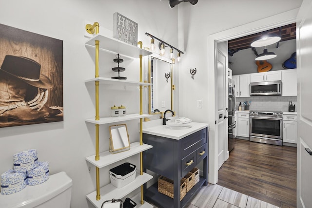 610 21st Ave N Unit 101, Nashville, TN 37203 - bathroom with decorative backsplash, vanity, toilet, and wood finished floors