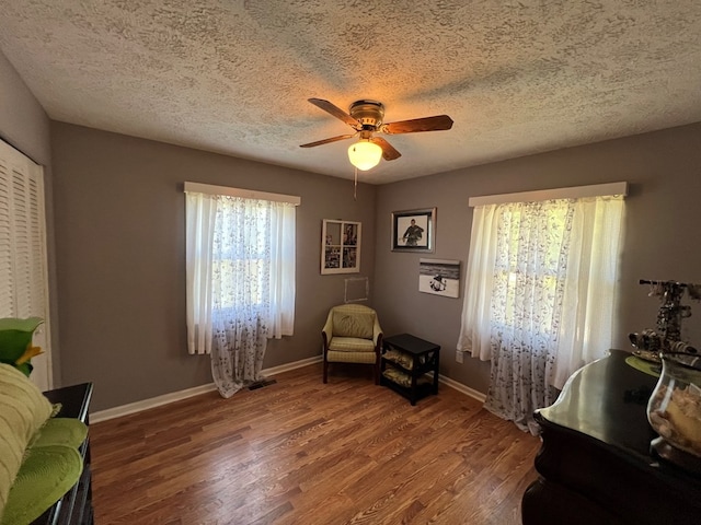 living area with dark hardwood / wood-style flooring, a textured ceiling, and ceiling fan