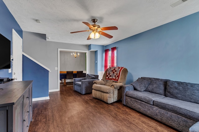 living room featuring a textured ceiling, ceiling fan with notable chandelier, and dark wood-type flooring