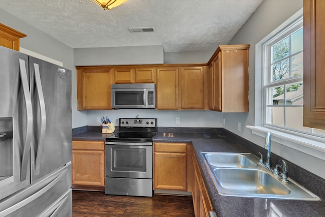 kitchen with sink, stainless steel appliances, a textured ceiling, and dark hardwood / wood-style flooring