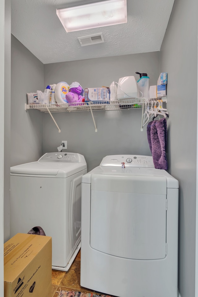 clothes washing area with tile patterned flooring, a textured ceiling, and separate washer and dryer